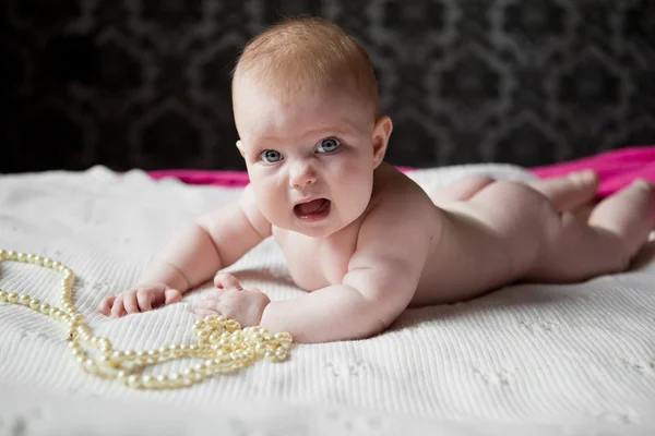 Petite fille mignonne bébé couché sur le tapis avec des perles de perles et nous — Photo