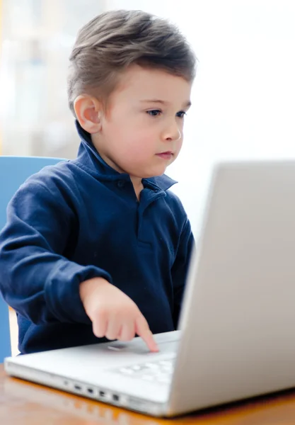Barn som sitter og leker med datamaskinen hjemme stockfoto