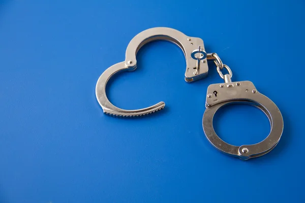 Open handcuffs with key on blue Stock Image