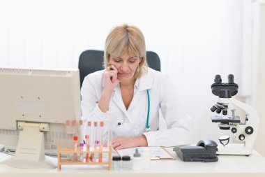 Concentrated middle age doctor woman working at office clipart