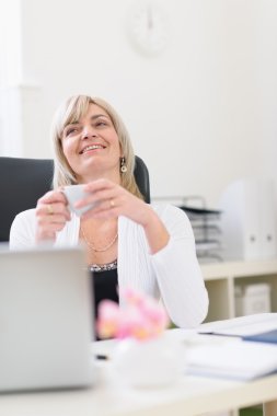 Middle age business woman having cup of coffee and dreaming clipart