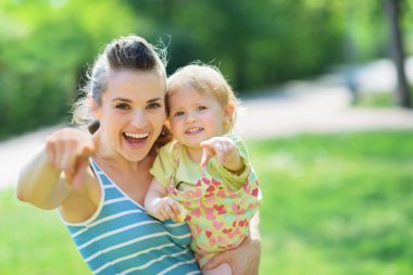 Happy mother and baby pointing in camera clipart