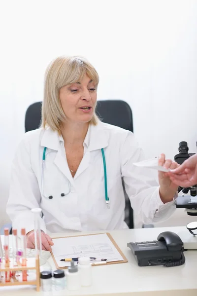 Średnim wieku kobieta lekarz daje receptę na pacjenta — Zdjęcie stockowe