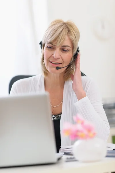 Middle age business woman with headset working on laptop — Stock Photo, Image