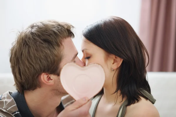 Kissing couple hiding behind Valentines heart — Stock Photo, Image