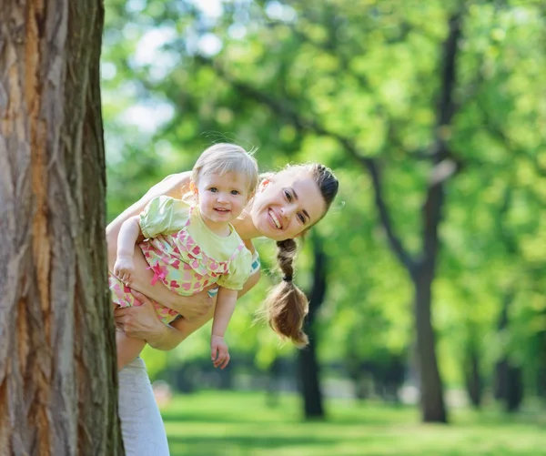 Счастливая мать и ребенок, выглядывающие из-под дерева — стоковое фото