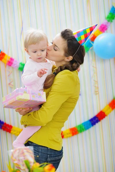 Mother kissing baby on birthday celebration party — Stock Photo, Image