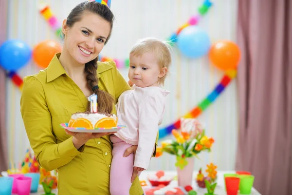 Mother holding baby and birthday party cake — Stock Photo, Image