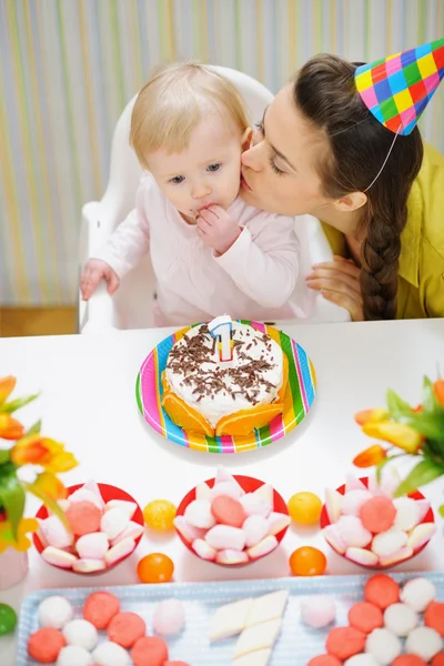 Mère embrasser bébé manger gâteau d'anniversaire — Photo