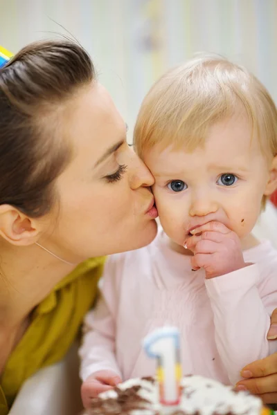 Mother kissing baby eating birthday cake — Stock Photo, Image