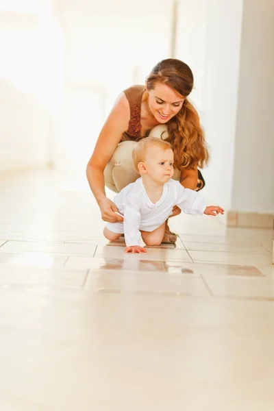 Happy mother helping baby to creep — Stock Photo, Image