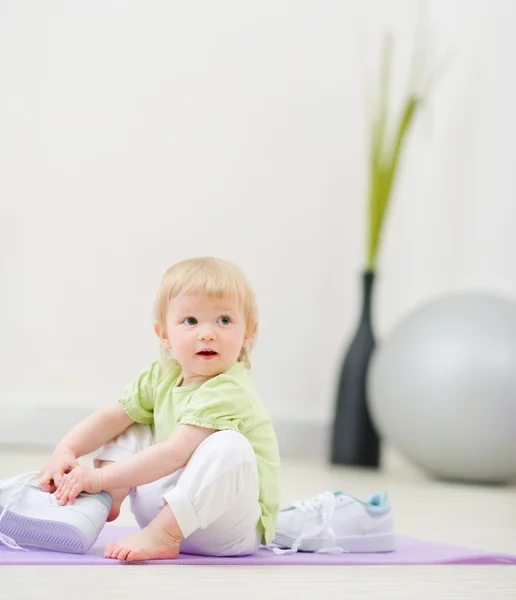 Baby trying to wear big sneakers — Stock Photo, Image