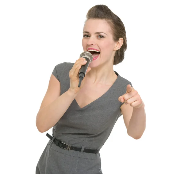 Happy woman singing in microphone and pointing on you isolated — Stock Photo, Image