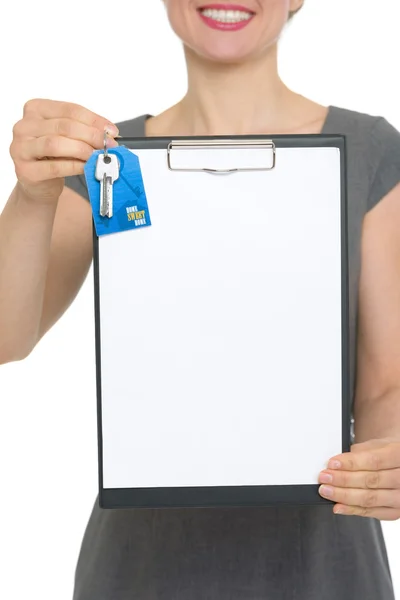 Closeup on blank clipboard and keys holding by happy female realtor — Stock Photo, Image