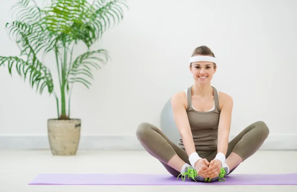 Smiling woman in sportswear making stretching exercises — Stock Photo, Image