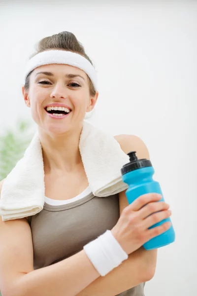 Счастливая фитнес-женщина с полотенцем на плечах, держа бутылку воды — стоковое фото
