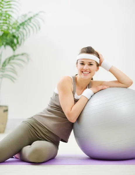 Mujer feliz sentada cerca de la pelota fitness —  Fotos de Stock