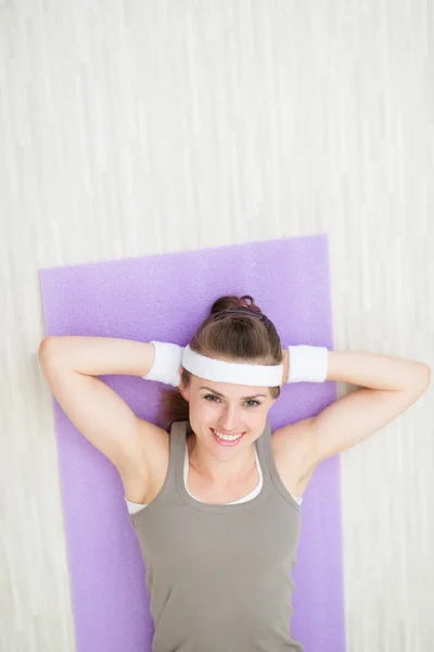 Улыбающаяся здоровая женщина ложится на фитнес-коврик — стоковое фото