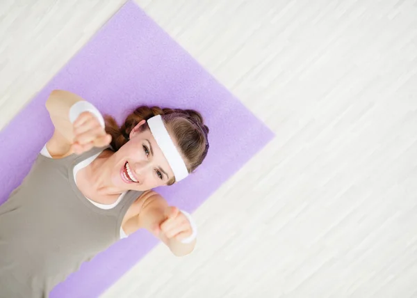 Femme souriante allongée sur un tapis de fitness et pointant vers vous — Photo