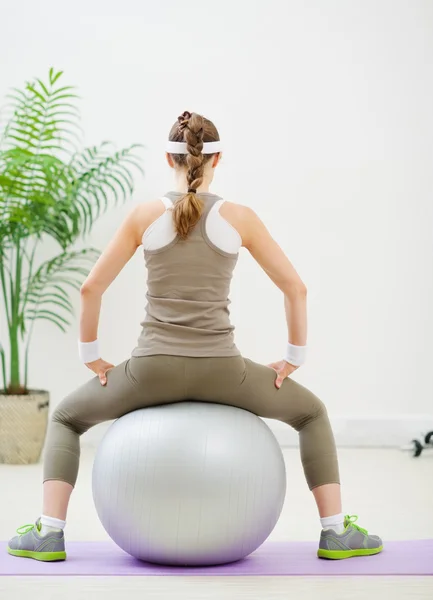 Smal kvinna sitter på fitness boll tillbaka till kamera — Stockfoto