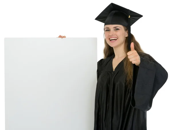 Feliz graduación estudiante chica sosteniendo cartelera en blanco y showin — Foto de Stock