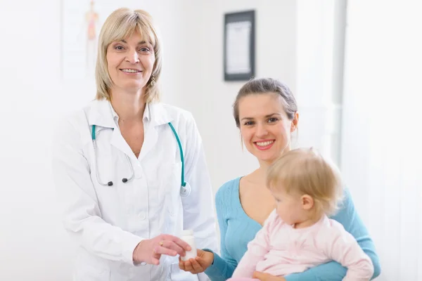 Middle age pediatric doctor giving tablets bottle to mother with Stock Picture