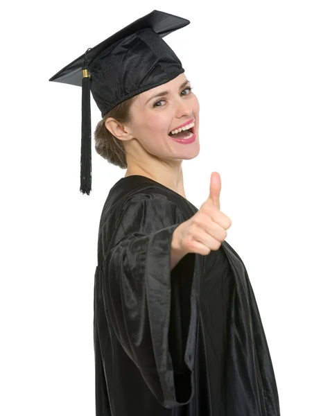 Sorridente laurea studente donna mostrando pollici su isolato Immagini Stock Royalty Free