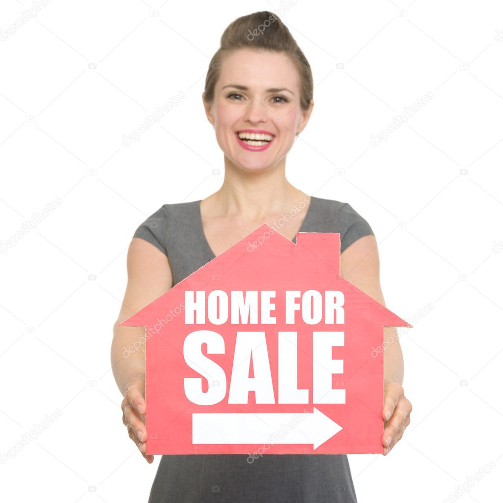 Portrait of smiling realtor showing home for sale sign isolated