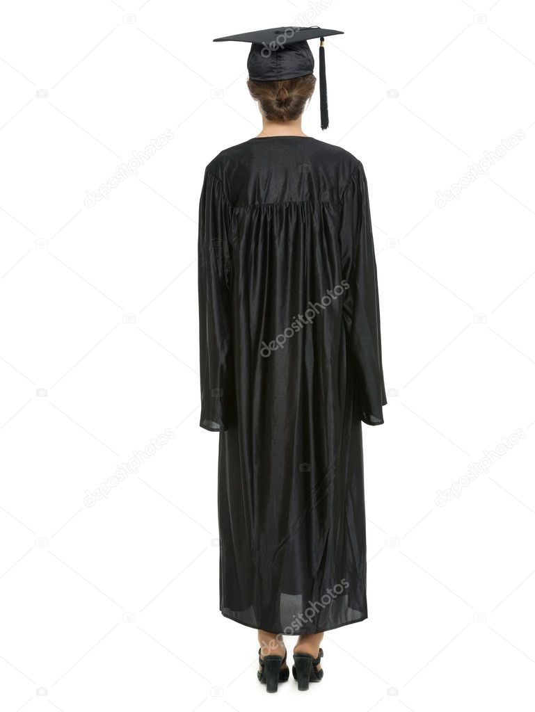 Full length portrait of female in graduation cap and gown standing back to camera