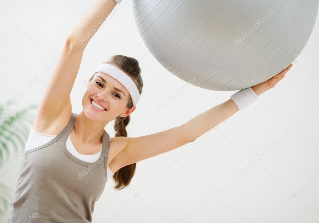 Smiling slim woman making exercises with fitness ball
