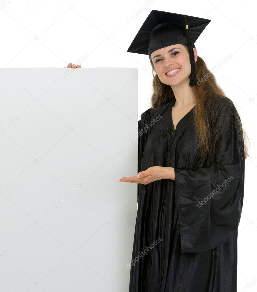 Smiling graduation student woman showing on blank billboard
