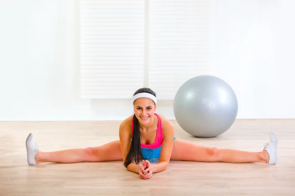 Sorridente ginnastica ragazza siting su palestra split — Foto Stock