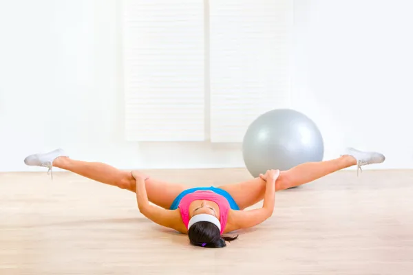 Chica flexible haciendo ejercicio de estiramiento en el suelo —  Fotos de Stock