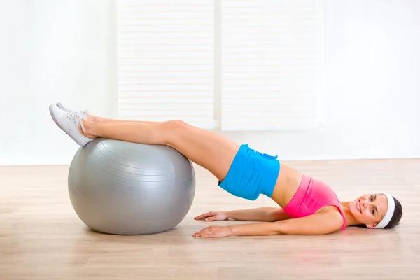 Sorrindo jovem mulher fazendo crunch abdominal na bola de fitness — Fotografia de Stock
