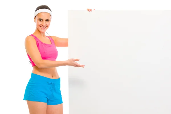 Счастливая фитнес-девушка в спортивной одежде держит пустой рекламный щит — стоковое фото