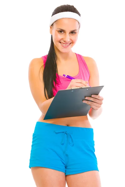 Sonriente mujer entrenador de fitness escritura en portapapeles —  Fotos de Stock