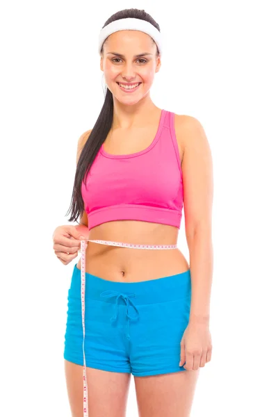 Улыбающаяся молодая девушка с идеальным спортивным телом, измеряющим ее талию — стоковое фото