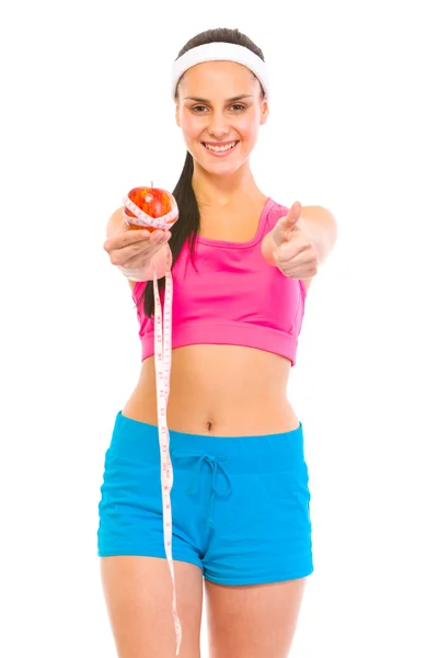 Улыбающаяся фитнес-женщина держит яблоко с измерительной лентой и шо — стоковое фото