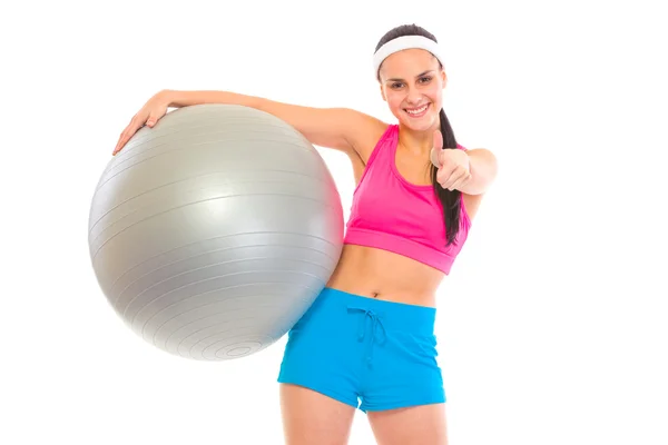 Sonriendo en forma chica joven con pelota de fitness mostrando los pulgares hacia arriba gesto — Foto de Stock