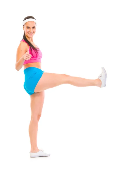 Полноразмерный портрет улыбающейся фитнес-девушки с поднятой ногой шо — стоковое фото