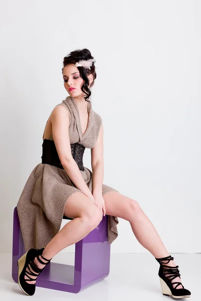Mode meisje zit op moderne stoel in studio — Stockfoto