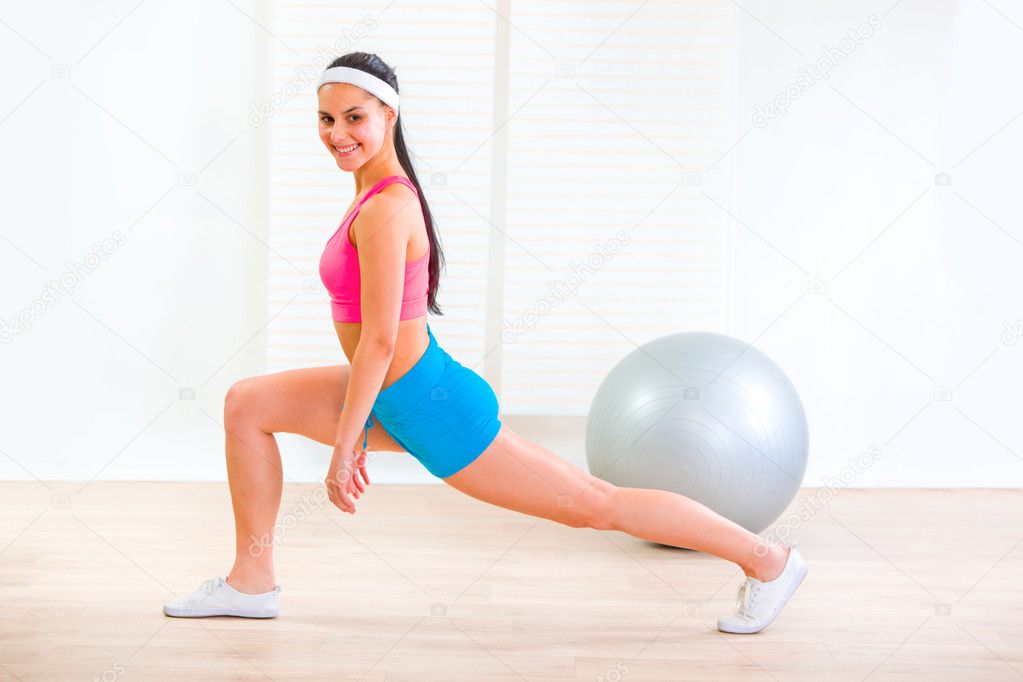 Smiling fitness young girl doing stretching exercises at home