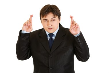 Superstitious young businessman holding crossed fingers