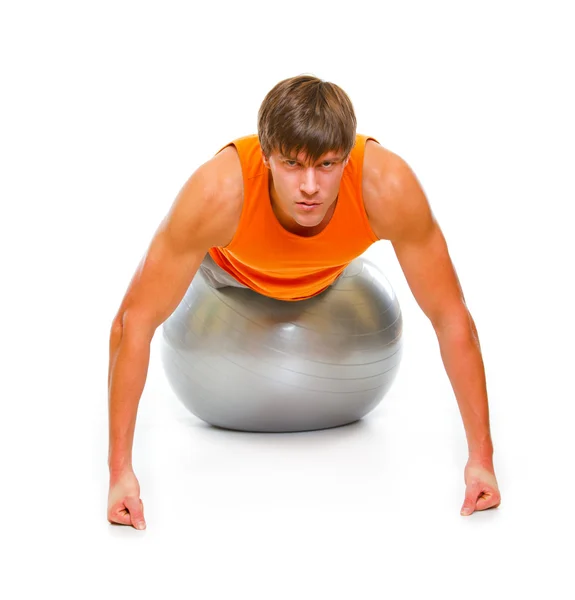 Young man in sportswear making push up exercise on fitness ball — Stock Photo, Image