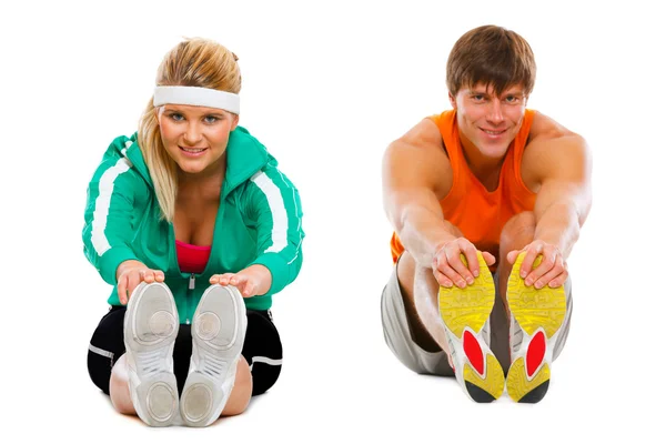 Девушка и парень в спортивной одежде сидят на полу и делают растяжку — стоковое фото