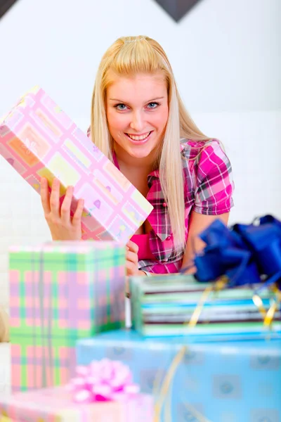 Happy pretty woman sitting on sofa and holding present in hands — Stockfoto