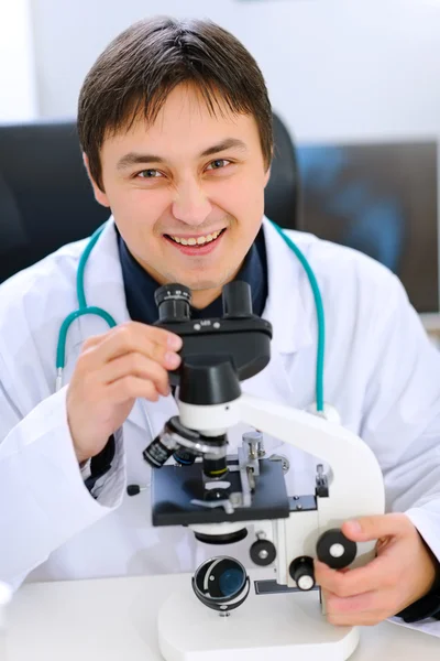 Uśmiechający się lekarza medycyny pracy z mikroskopem w laboratorium — Zdjęcie stockowe