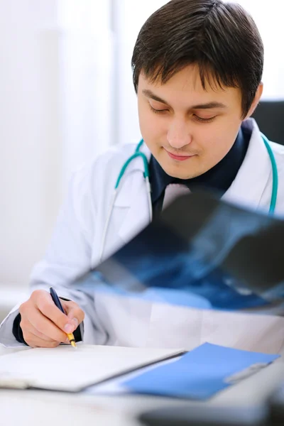 Médico analizando pacientes roentgen y escribiendo resultados i — Foto de Stock