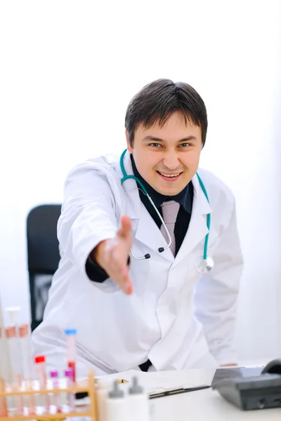 Smiling medical doctor stretches out hand for handshake in offic — Stock Photo, Image