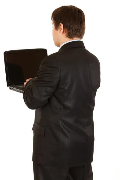 Uomo d'affari in piedi di nuovo alla fotocamera e lavorare sul computer portatile — Foto Stock